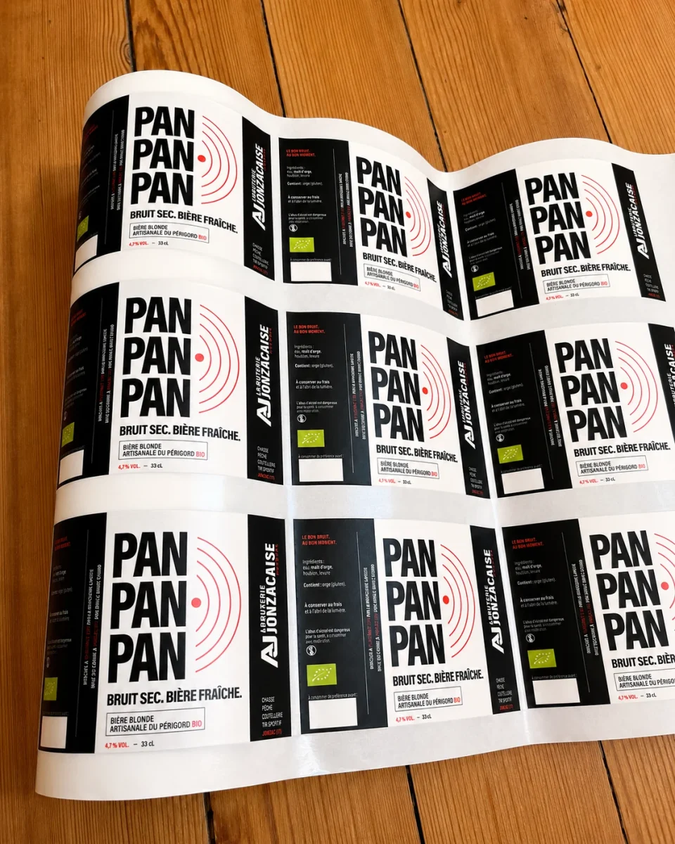 Photographie d’une planche souple d’étiquettes PAN PAN PAN imprimées, étendue sur une table en bois.