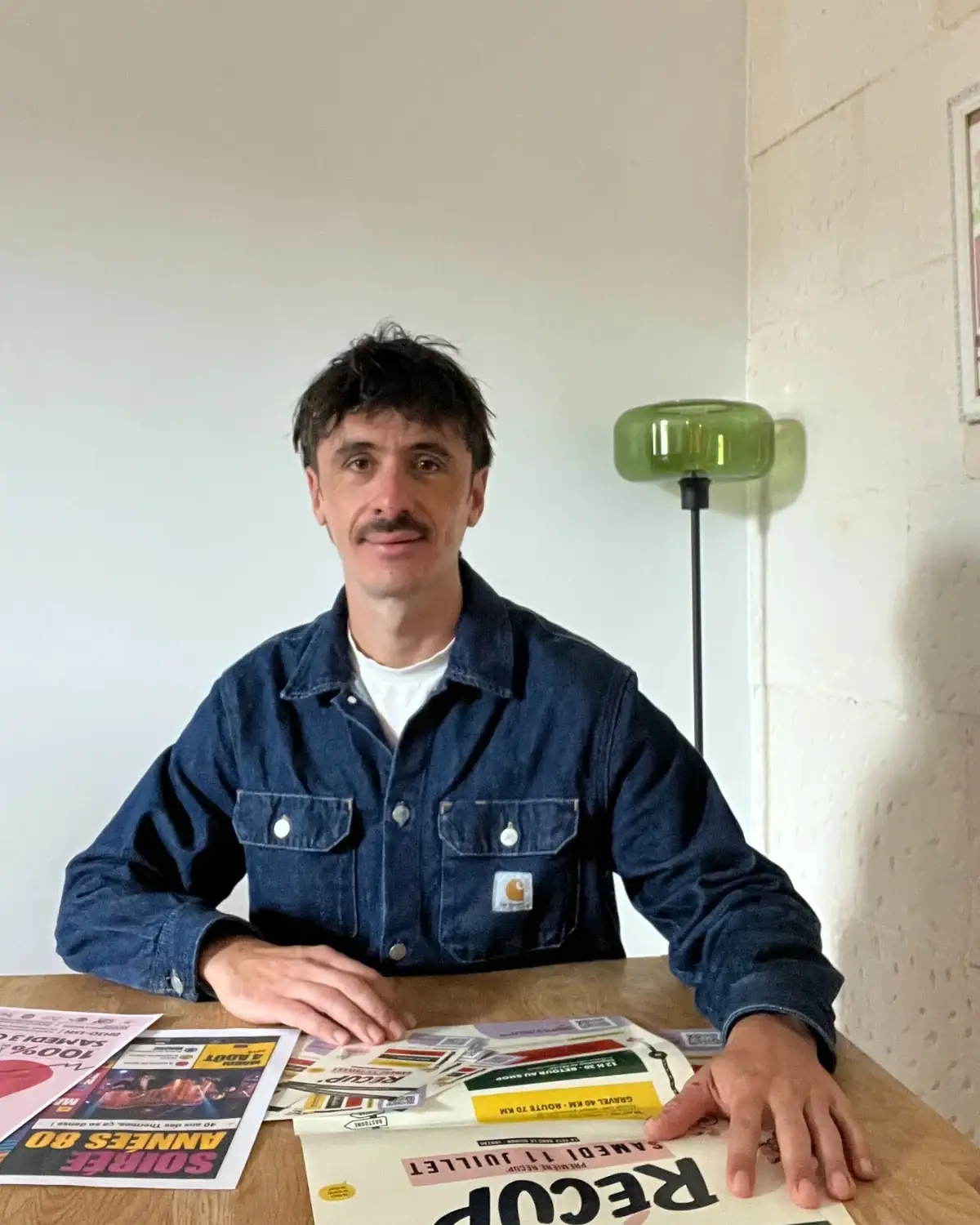 Cédric Chamoulaud, à la table de son studio, entouré de ses créations graphiques, à Jonzac.